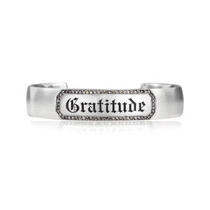 Engraveable sterling silver cuff bracelet with champagne diamond border around engraved "Gratitude" in gothic letters